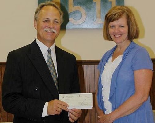 Grand Knight Dan Hampton (left) presents Cardinal Services CEO Jane Wear (right) with their donation.
